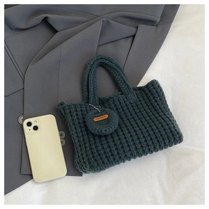 Detail of dark green woven bag with handcrafted leather tag and round charm accessory