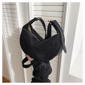 Detail of black suede hobo bag featuring wide adjustable strap and gold hardware accents