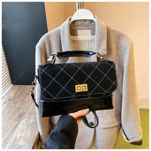Detail of black quilted shoulder bag featuring matte finish and gold square twist lock