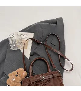 Détail du sac à main vintage en cuir marron avec bandoulière et pendentif ours peluche