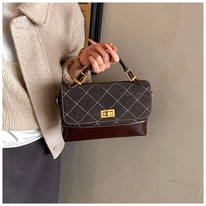 Detail of dark brown quilted leather handbag with gold twist lock and white stitching