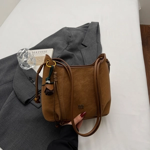 Detail of vintage brown shoulder bag with leather texture and delicate floral tassel