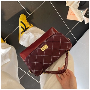 Macro view of burgundy rhombic pattern handbag with gold clasp and white stitching