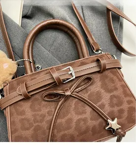 Gros plan d'un sac à main en daim marron avec pendentif étoile, nœud et boucles