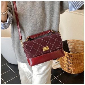 Burgundy quilted crossbody bag with white stitching and gold twist lock on model