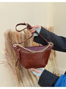 Détail d'un sac ceinture en cuir marron vintage avec chaîne dorée et zip à pompon long