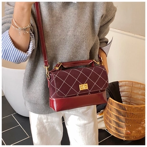Detail view of retro burgundy crossbody bag with quilted diamond pattern and gold lock