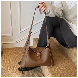 Détail d'un sac à bandoulière en cuir marron avec texture litchi et boucle en métal doré