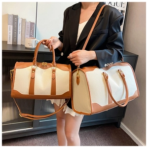 Detail of canvas travel bag set with brown leather trim and golden metal hardware