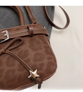 Gros plan du sac marron en faux daim avec pendentif étoile argenté et boucle
