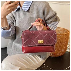 Close-up of burgundy leather bag with white quilted stitching and gold metal twist lock