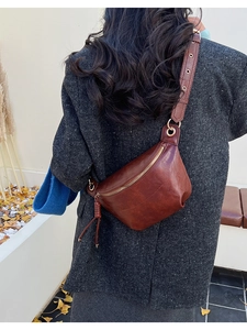 Détail du sac bandoulière vintage en cuir marron avec pompon et dorures