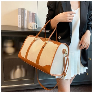 Detail of canvas travel bag with brown leather trim and adjustable shoulder strap