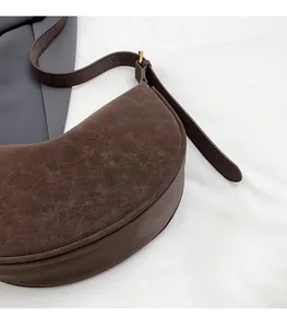 Detailed macro view of dark brown dumpling bag featuring matte vintage leather texture
