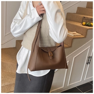 Sac bandoulière marron en cuir grainé porté avec une tenue de bureau élégante sur un escalier