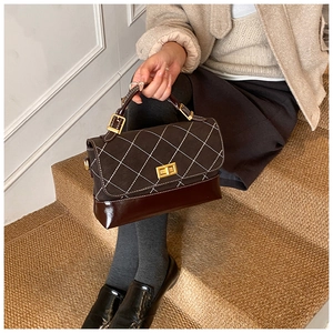Close-up of stylish quilted small square bag with gold twist lock and top handle