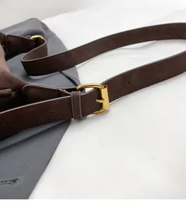 Detail view of adjustable dark brown matte shoulder strap with gold metal buckle