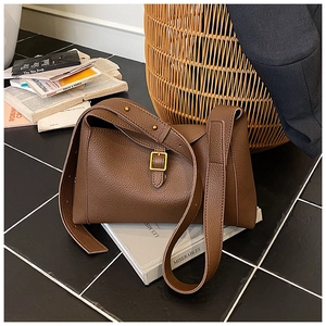 Détail du sac bandoulière en cuir grainé marron café avec large sangle et boucle dorée