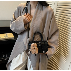 Détail du sac à main noir à motif léopard avec boucle décorative et charm chien peluche