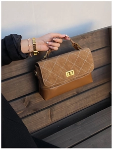 Close-up of retro brown quilted flap bag with gold twist lock on wooden bench