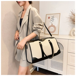 Model showing large canvas travel bag with leather trim in a modern home setting