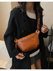 Détail d'un sac bandoulière vintage en cuir souple marron avec fermeture éclair dorée en métal