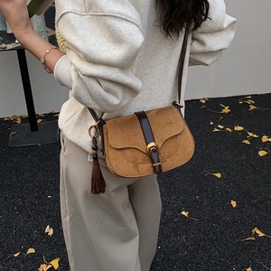 Vintage brown saddle bag with fringe tassel shown on model in an outdoor autumn setting