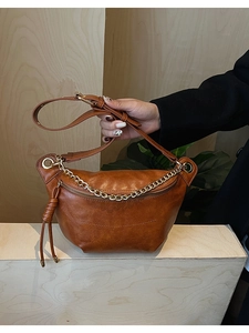 Sac bandoulière demi-lune en cuir marron avec chaîne dorée et breloque à pompon chic