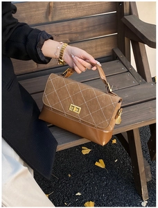 Close-up of retro brown quilted handbag with gold square lock on a wooden bench