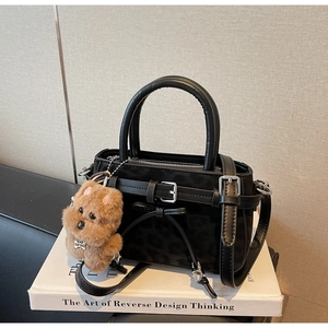 Détail du sac à main noir à imprimé léopard avec breloque chien en peluche et boucle
