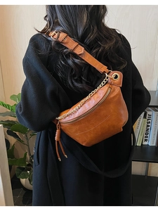 Détail du sac banane en cuir souple marron-orange avec chaîne en métal et bandoulière large