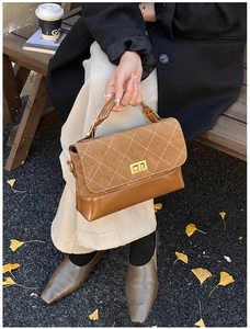 Close-up of stylish brown quilted handbag with gold clasp in an autumn park setting