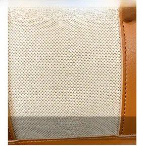 Detailed close-up of cream woven canvas and brown leather trim with yellow stitching
