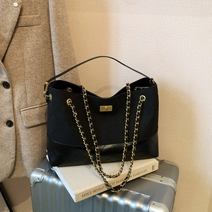 Chic black matte quilted tote with golden chain strap on a vintage suitcase