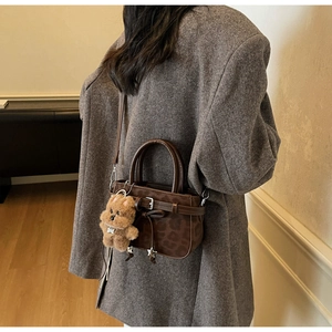 Détail du sac à main léopard avec breloque étoile, ours en peluche et blazer marron
