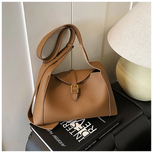 Sac à épaule en cuir litchi marron avec boucle en métal doré dans un décor intérieur