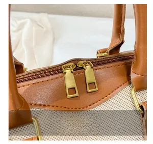 Close-up of golden dual metal zippers and fine stitching on a canvas and leather bag
