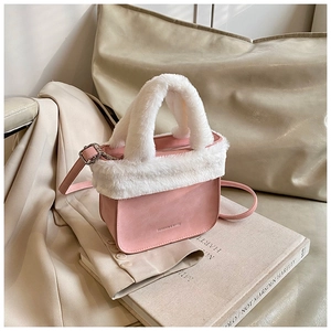 Close-up of pink suede bucket bag with white faux fur trim and silver metallic buckle detail