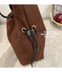 Detail of drawstring design on brown suede bucket bag with gold metal eyelets