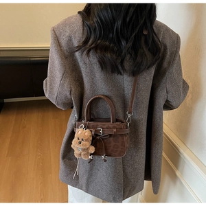 Détail d'un sac bandoulière à imprimé léopard texturé avec un charmant pendentif chiot