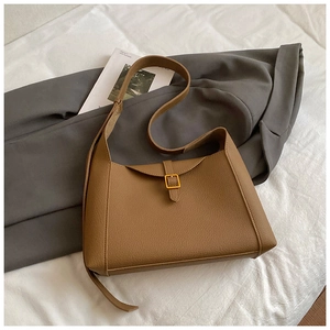 Détail du sac bandoulière marron motif litchi avec boucle dorée sur un blazer gris