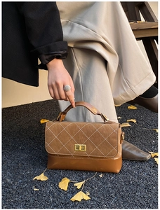 Detail of dark brown leather handbag with diamond stitching and golden turn-lock clasp