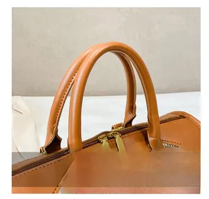 Detail of leather handles and dual gold zippers on a canvas patchwork travel bag