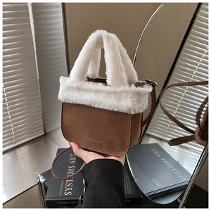 Detail of plush faux fur trim on a brown suede bucket bag with top handles and strap
