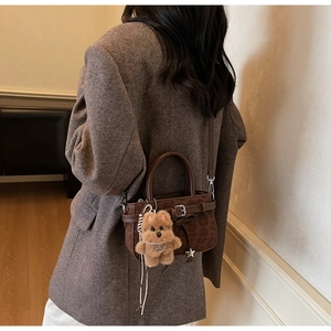 Détail du sac léopard en daim avec breloque ours en peluche et boucle rétro chic