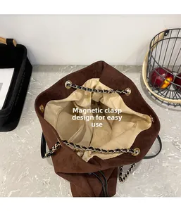 Detail view of the brown suede bucket bag featuring a secure magnetic closure and chain strap