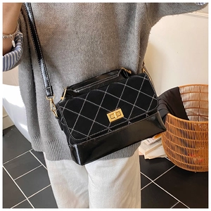Detail of black quilted shoulder bag with white contrast stitching and gold twist lock