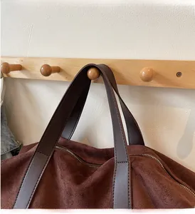 Détail d'un grand sac cabas en daim marron foncé avec poignée en cuir et fermeture éclair