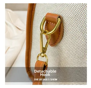 Macro detail of golden detachable metal hook with leather trim on canvas travel bag