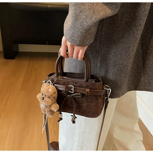 Détail du sac à main léopard en daim marron avec une breloque d'ours en peluche mignon
